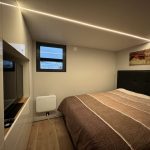Großes Schlafzimmer mit Boxspringbett und Smart TV